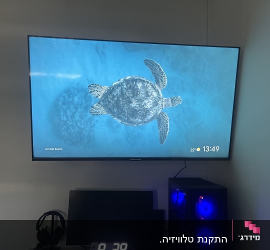 מסך טלוויזיה תלוי על הקיר עם מחשב מתחת